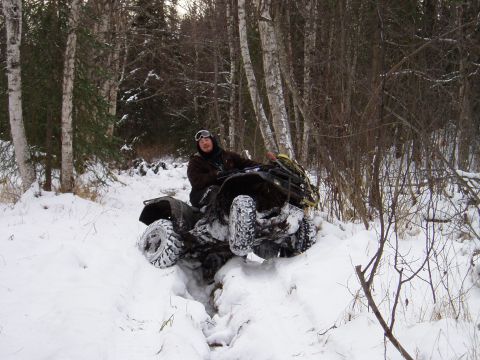 2000 Ford E350 - An all-terrain vehicle navigates a snow-covered trail in a wooded area.