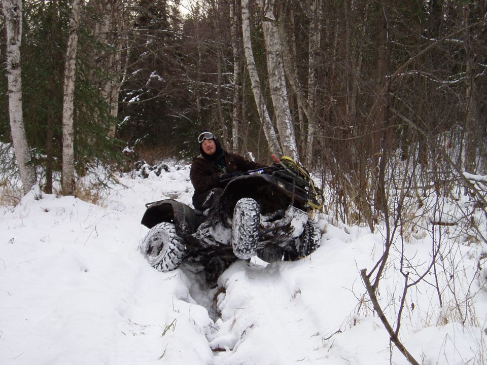 Black all-terrain vehicle with a rider in a snowy forest