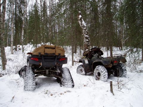 2000 Ford E350 - Two ATVs with tracks are in the snow, one carrying a cargo bag.