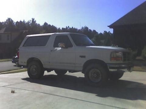 1996 Ford Bronco - A white SUV is parked in a driveway on a sunny day. The vehicle is viewed from the front quarter angle.