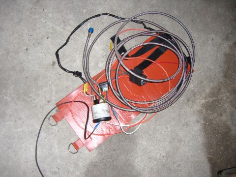 1988 Ford Bronco - An automotive part, possibly a fuel pump assembly, lies on a concrete surface with various wires and hoses attached.