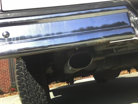 1996 Ford Bronco - Close-up of a vehicle's rear bumper and exhaust pipe, with a tire visible.