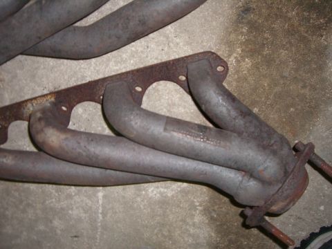 1988 Ford Bronco - Close-up of a used exhaust manifold, showing signs of wear and rust on the mounting hardware.