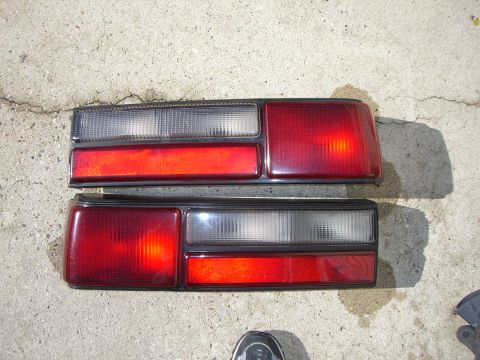 1988 Ford Bronco - A pair of red and clear car tail lights are shown resting on a concrete surface.