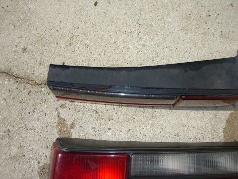 1988 Ford Bronco - Close-up of two car tail lights, one positioned above the other, resting on a concrete surface.