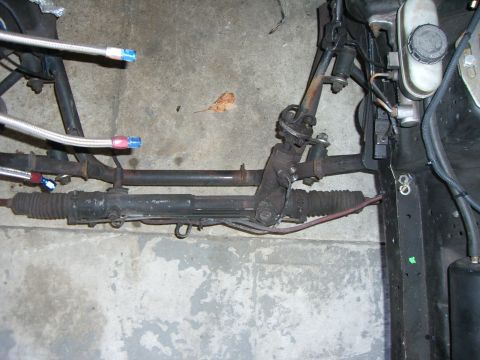 1988 Ford Bronco - Close-up of a vehicle's power steering rack and pinion assembly, showing braided hoses.