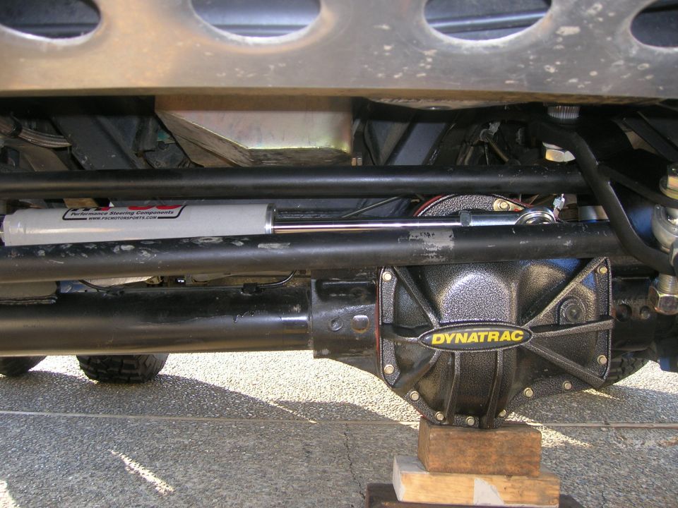 Undercarriage of a vehicle showing a Dynatrac differential cover and a steering stabilizer shock