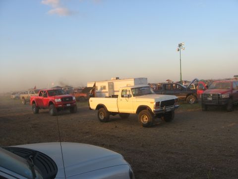 1979 Ford Bronco - Multiple trucks and RVs are parked in an outdoor area, possibly a fairground or event site.