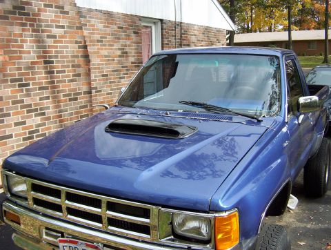 1986 Toyota Hilux - Blue 1986 Toyota Hilux pickup truck parked in front of a brick building.
