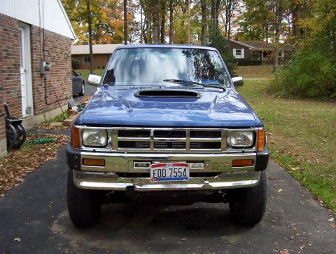 1986 Toyota Hilux - A blue pickup truck is parked in a driveway with fall foliage in the background.