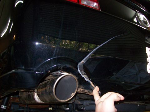 2007 Ford Mustang - Rear bumper damage on a 2007 Ford Mustang, revealing underlying metal and exhaust system.