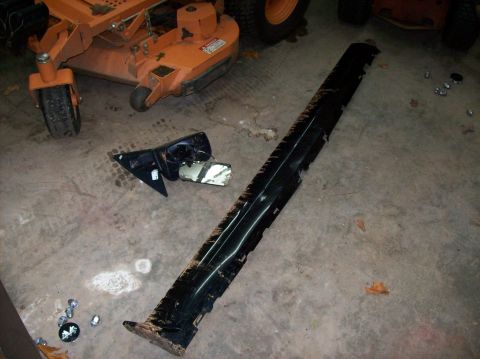 2007 Ford Mustang - A detached car side skirt and side mirror lie on a concrete floor near a lawn mower.