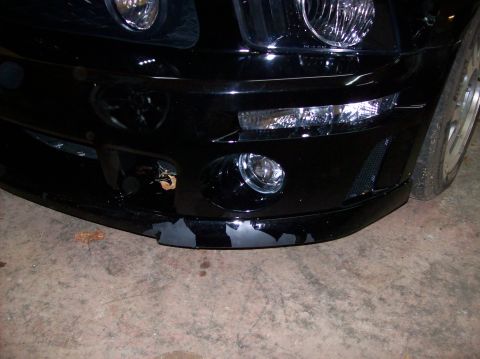 2007 Ford Mustang - Front bumper of a black car shows significant paint damage along the lower edge.