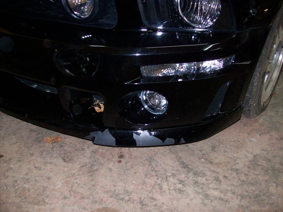 Black car front bumper with peeling paint and fog lights