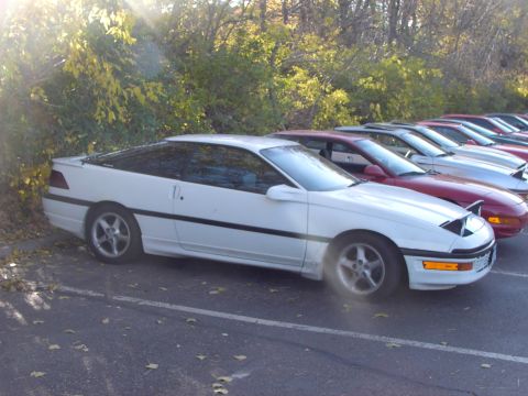 1991 Ford Probe - A row of cars, including a white 1991 Ford Probe, parked outdoors.