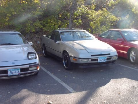 1991 Ford Probe - Three coupes are parked in a lot, with the central vehicle identified as a 1991 Ford Probe.