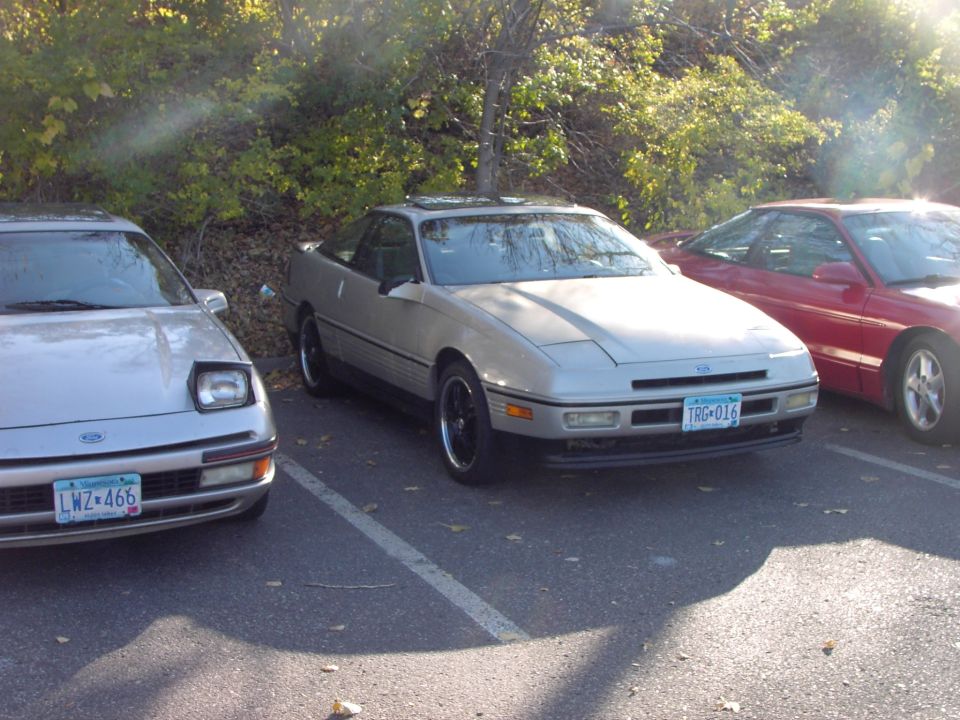 Silver 1991 Ford Probe coupe parked, front 3/4 view, with a red car to the right and a silver car to the left