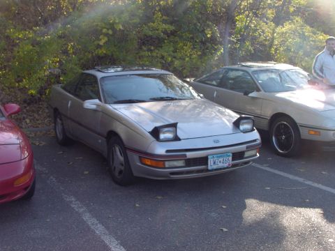 1991 Ford Probe - A silver 1991 Ford Probe is seen parked in a lot with other vehicles, its distinctive pop-up headlights.