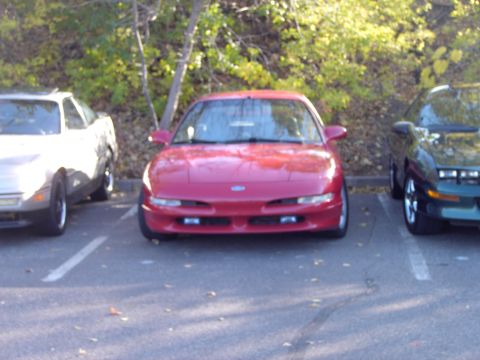 1991 Ford Probe - A red coupe is parked in a lot, with other vehicles visible on either side.
