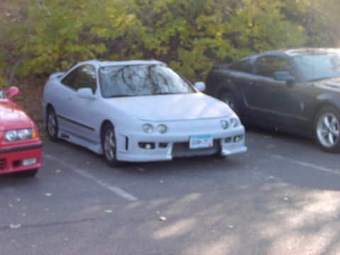1991 Ford Probe - A white coupe is parked in a lot with other vehicles, with trees in the background.