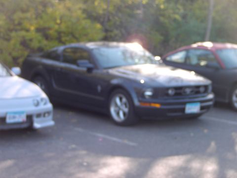 1991 Ford Probe - A dark blue Ford Mustang is parked in a lot next to other vehicles.
