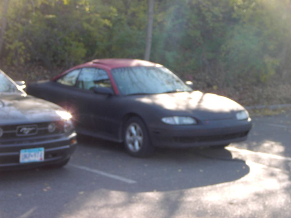 Dark coupe with red roof parked next to a Ford Mustang