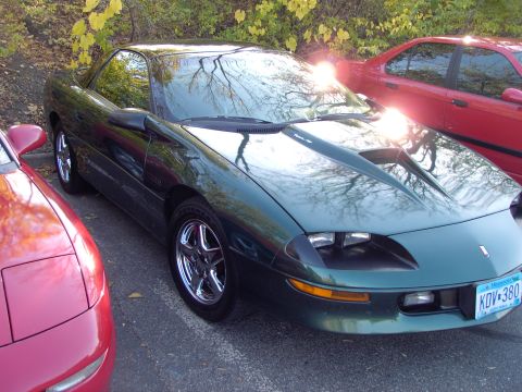 1991 Ford Probe - This green coupe features a prominent hood scoop and aftermarket wheels, parked next to other vehicles.