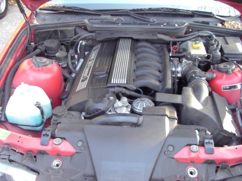 1991 Ford Probe - The engine bay of a red car is shown, a V12 engine and various fluid reservoirs.