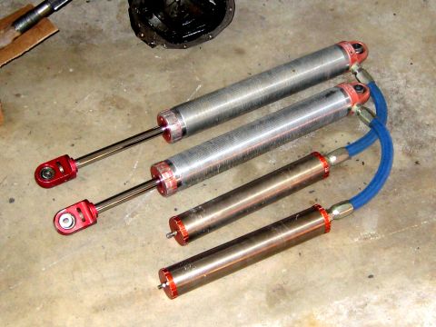 1996 Ford Bronco - Four shock absorbers, two with blue hoses, and a differential are laid out on a concrete surface.