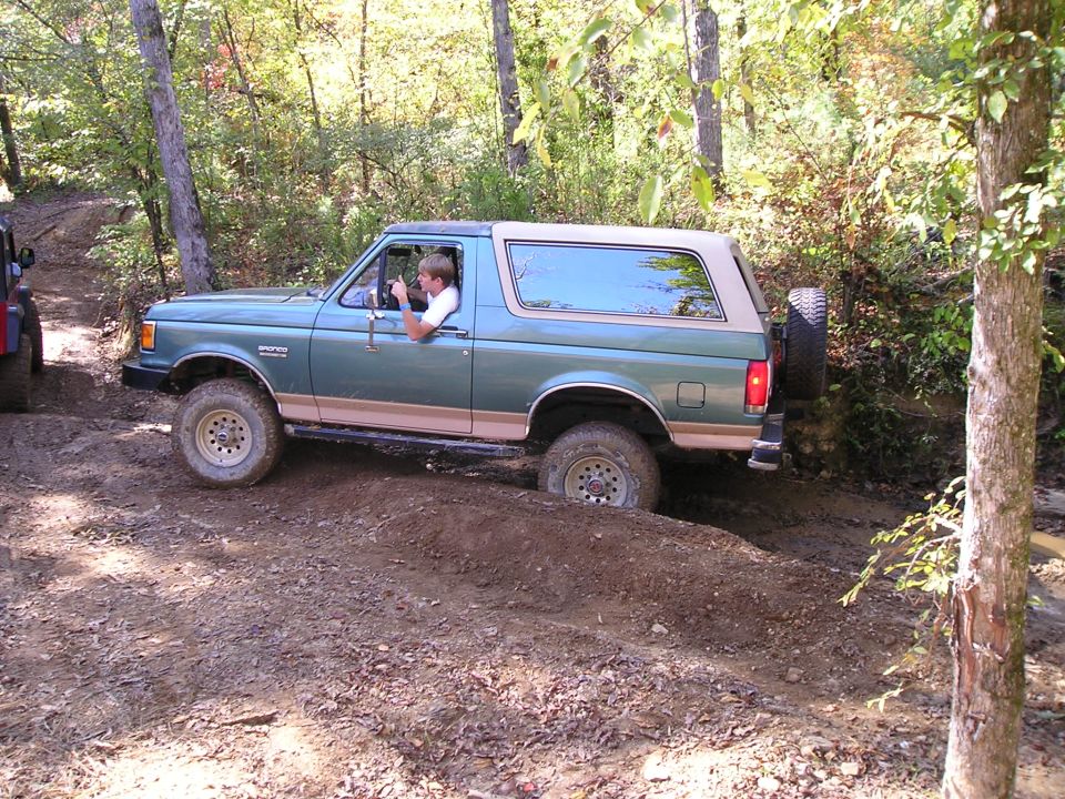 Green 1989 Ford Bronco navigating a dirt trail