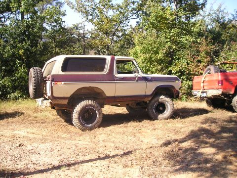 1989 Ford Bronco - Two trucks parked off-road, one a classic Ford Bronco and the other a red pickup.