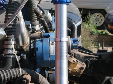 1983 Ford F-250 - Close-up of an engine bay a blue component and a silver shock absorber, with a trailer in the background.