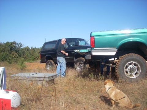 1992 Ford Bronco - A black 1992 Ford Bronco is parked next to a tall green truck in a grassy, outdoor area.