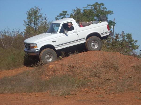 1992 Ford Bronco climbing a dirt hill with two people inside