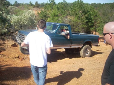1992 Ford Bronco - A green pickup truck is seen off-road with two people nearby.