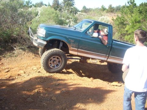 1992 Ford Bronco - Ford F-series pickup truck navigating an off-road trail with a lifted suspension.