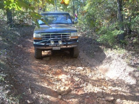 1992 Ford Bronco - This 1992 Ford Bronco navigates a rocky off-road path surrounded by trees.
