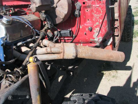 1983 Ford F-250 - The engine bay shows rusty exhaust pipes and various mechanical parts against a red background.