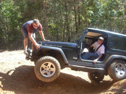 1992 Ford Bronco - Two men are on a dirt trail with a black Jeep Wrangler Rubicon. One man is standing on the fender while the other is in the driver's seat.
