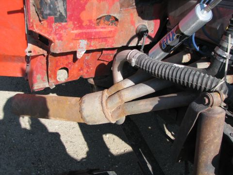 1983 Ford F-250 - Close-up of rusty exhaust pipes and suspension components on a red vehicle, likely from the early 1980s.