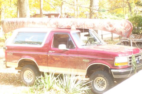 1993 Ford Bronco - A red 1993 Ford Bronco is pictured with a canoe strapped to its roof.