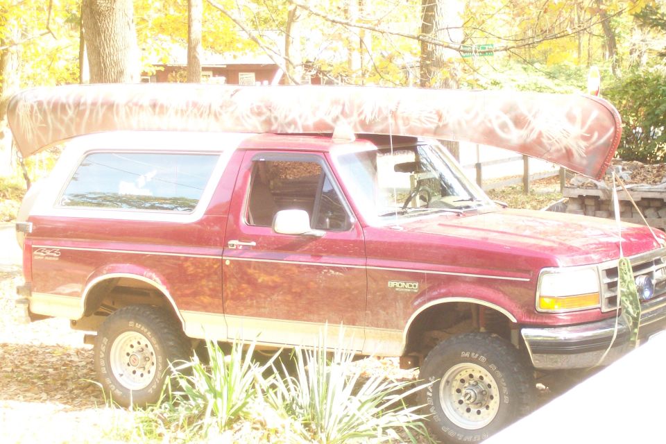 Red 1993 Ford Bronco with canoe on roof