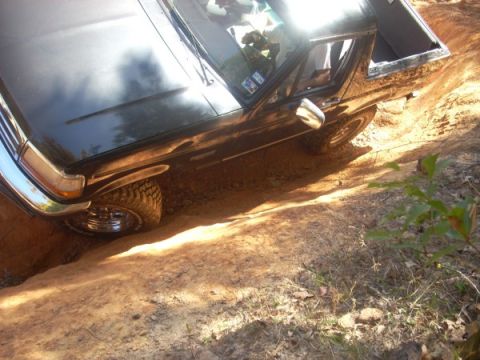 1992 Ford Bronco - This 1992 Ford Bronco is navigating a challenging off-road terrain with one wheel in a deep rut.