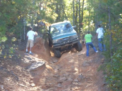 1992 Ford Bronco - A 1992 Ford Bronco navigates a challenging off-road course on a sunny day.