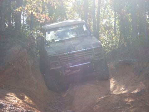 1992 Ford Bronco - This 1992 Ford Bronco navigates a challenging off-road trail, its tires digging into the mud as it ascends a steep incline.