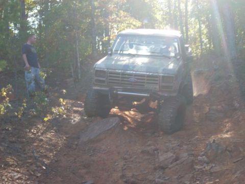 1992 Ford Bronco - Ford Bronco tackling a challenging off-road course with a person observing.