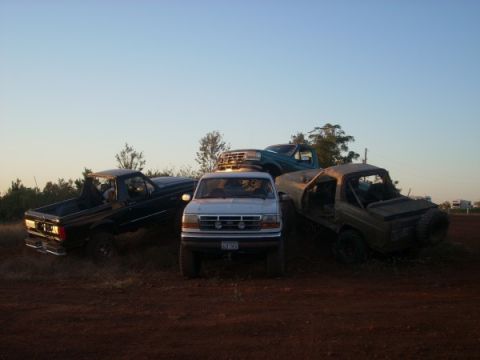 1992 Ford Bronco - Several trucks and SUVs are parked together on a dirt lot under a clear sky.
