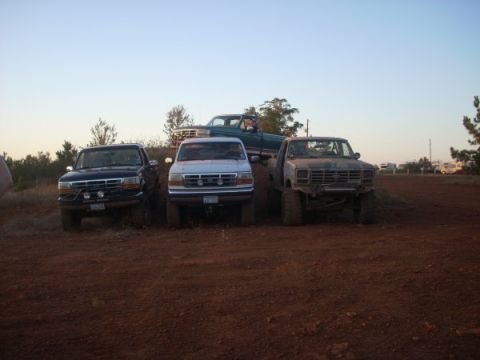 1992 Ford Bronco - Three Ford trucks and a green pickup truck are parked on a dirt hill under a clear sky.