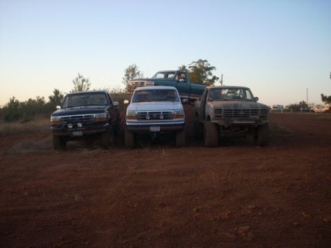 1992 Ford Bronco - Several trucks are parked on a dirt embankment under a clear sky.