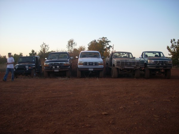 Jeep, two Ford Broncos, and two Ford F-Series trucks parked in dirt